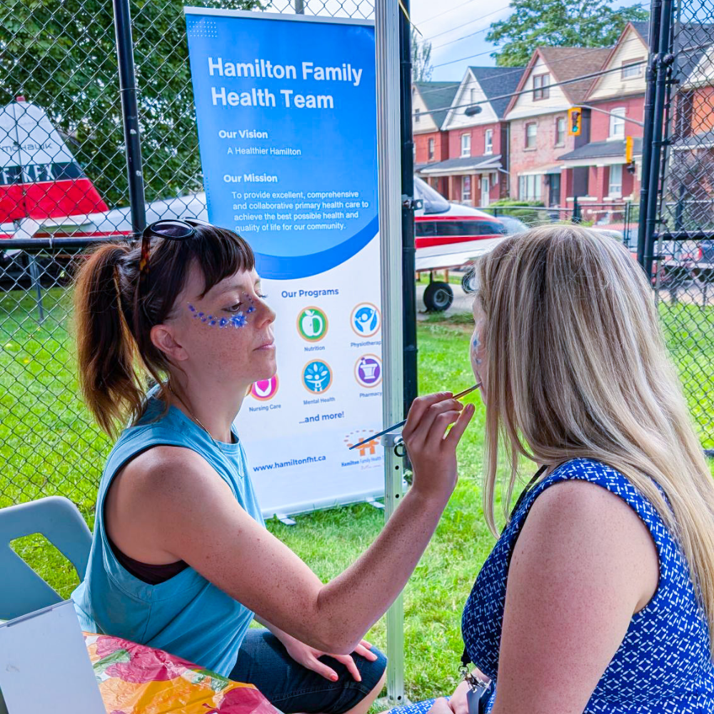 An HFHT staff member does face painting at an outreach event at the Eva Rothwell Centre.