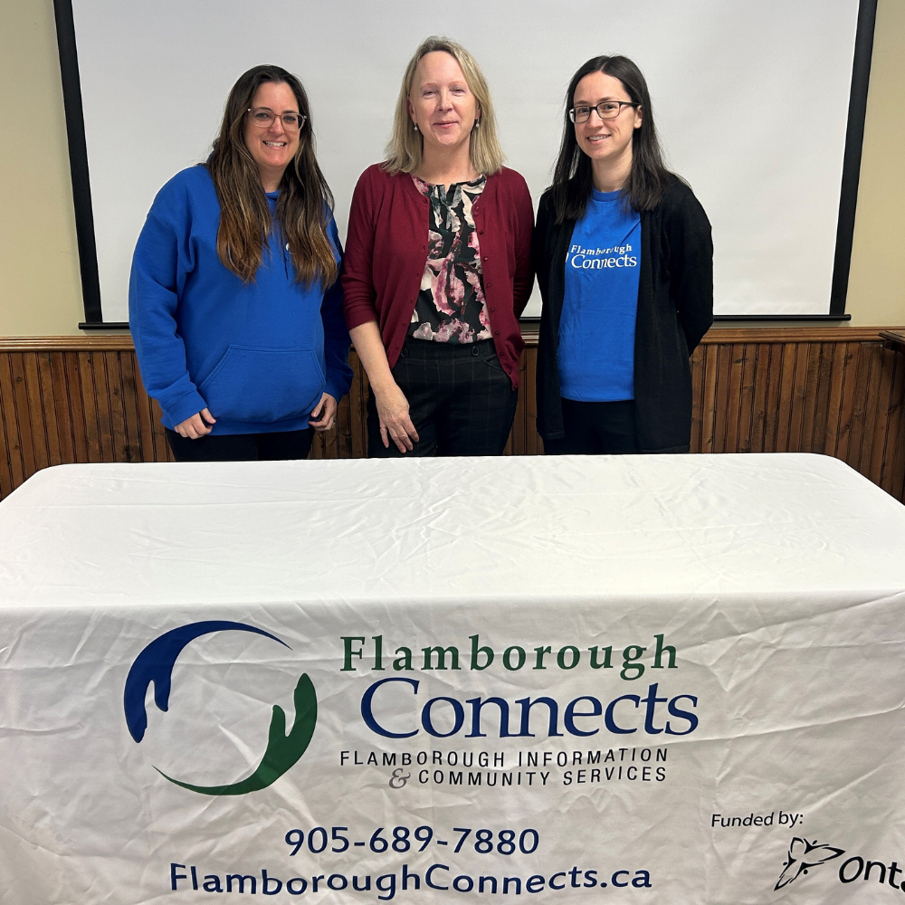 An HFHT staff member stands with two members of Flamborough Connects at an outreach event.