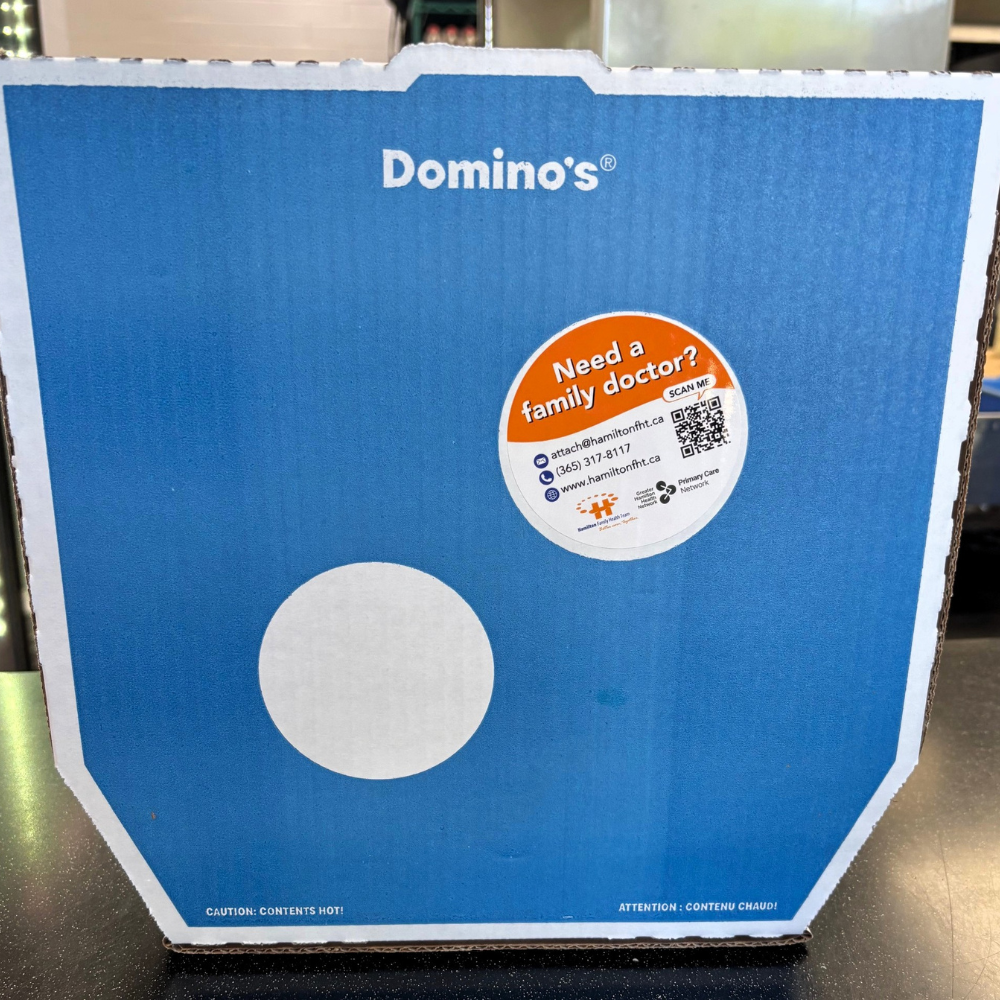 A Domino's pizza box with a sticker on it that says "Need a family doctor?".