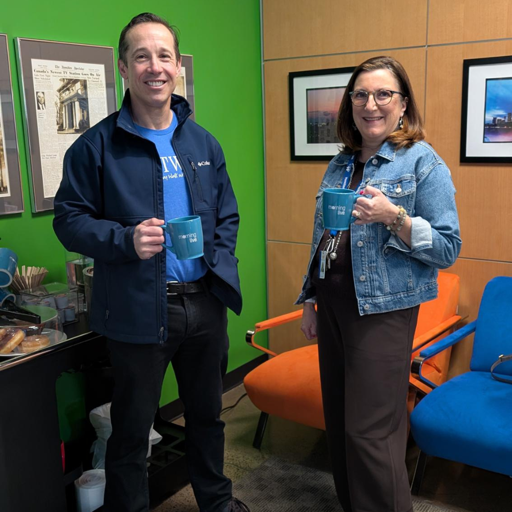 Two HFHT staff members stand inside the CHCH television studio holding CHCH mugs.