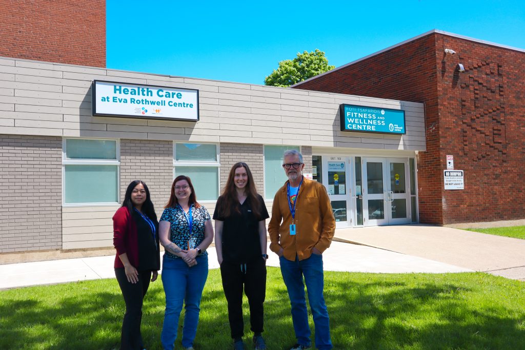 A group of people, standing on grass, in front of the Eva Rothwell building.