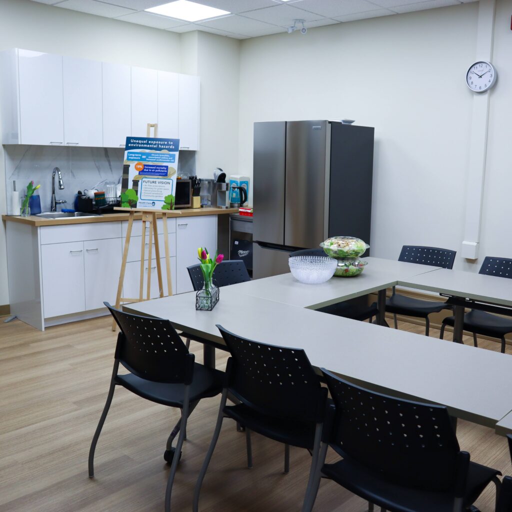 A new kitchen with a fridge, sink, and tables.