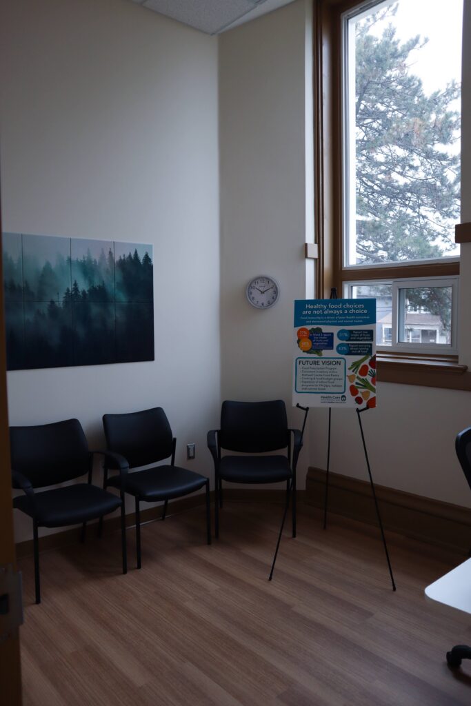 A room with large windows, chairs and a print of trees.
