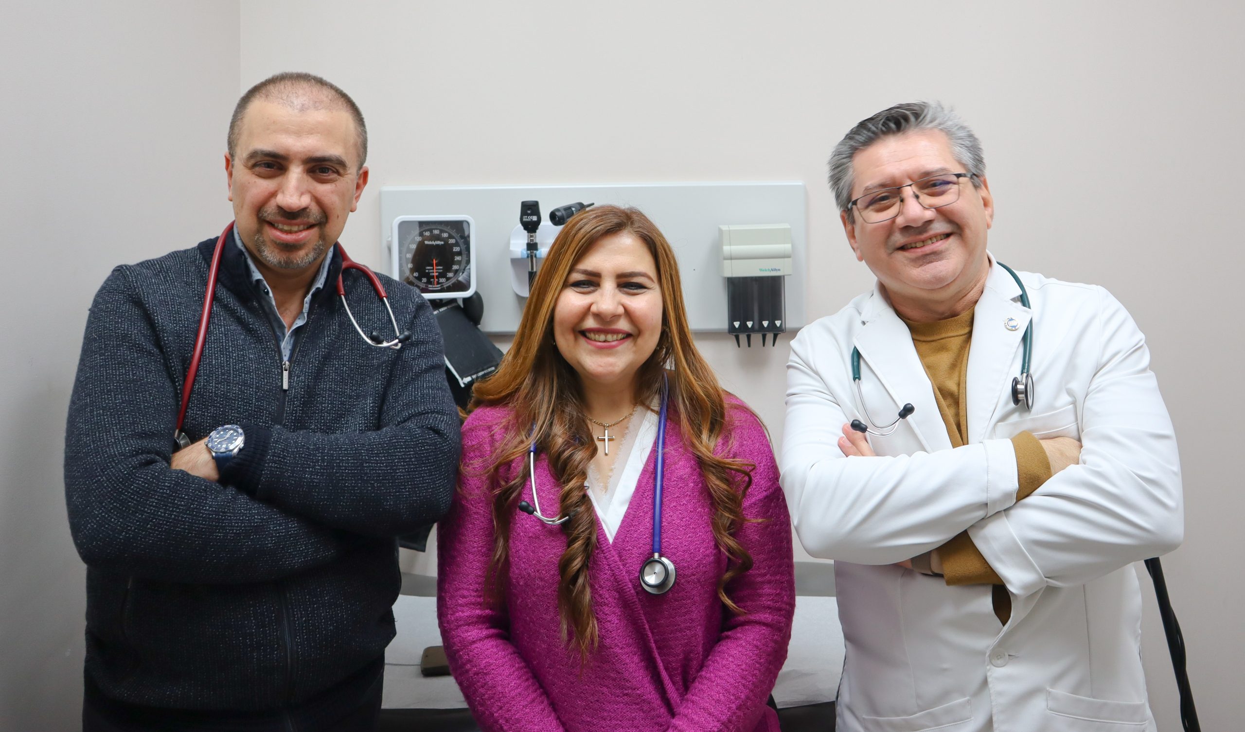 Three family doctors wearing stethoscopes smile at the camera.