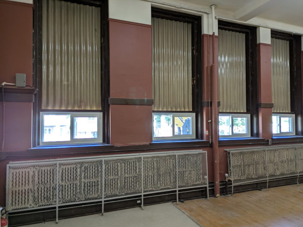 A wall with small windows, red paint and old radiators.
