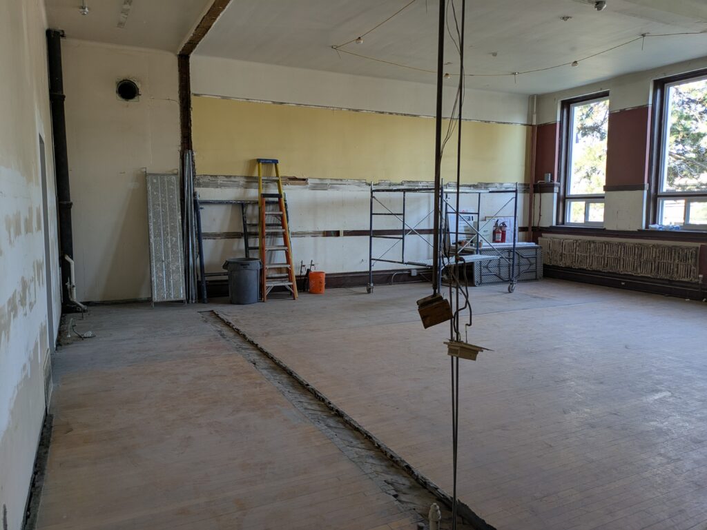 A room under construction where a wall has been removed and new windows have been installed.