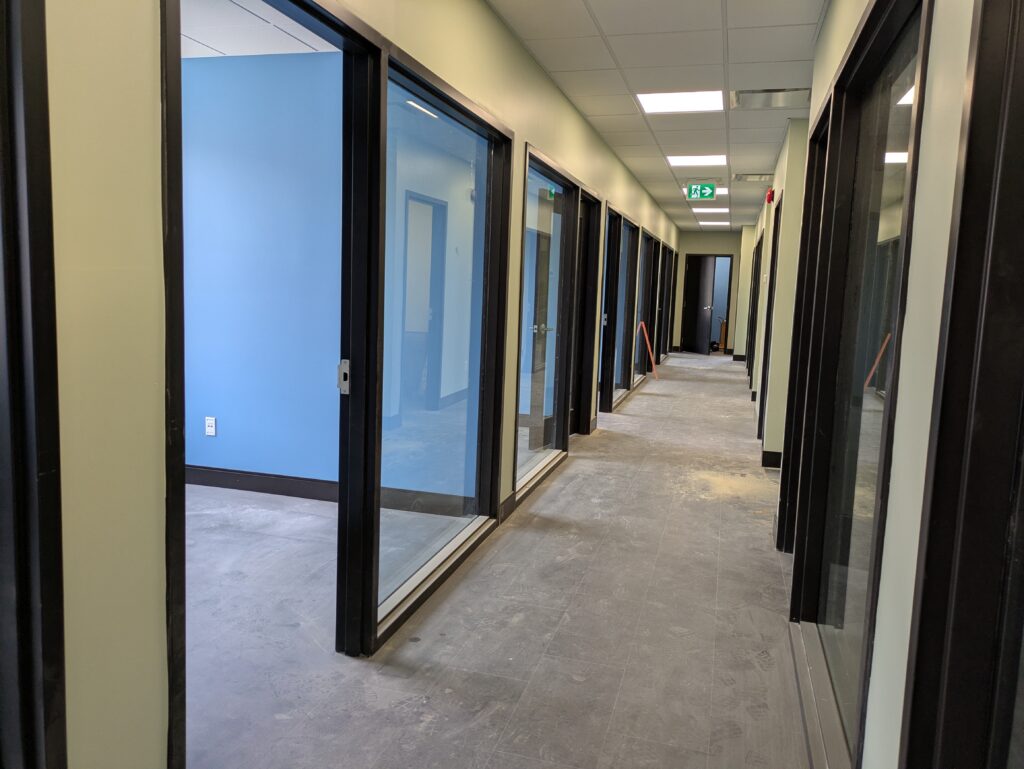 A hallway with many glass doors looking into rooms with blue walls.