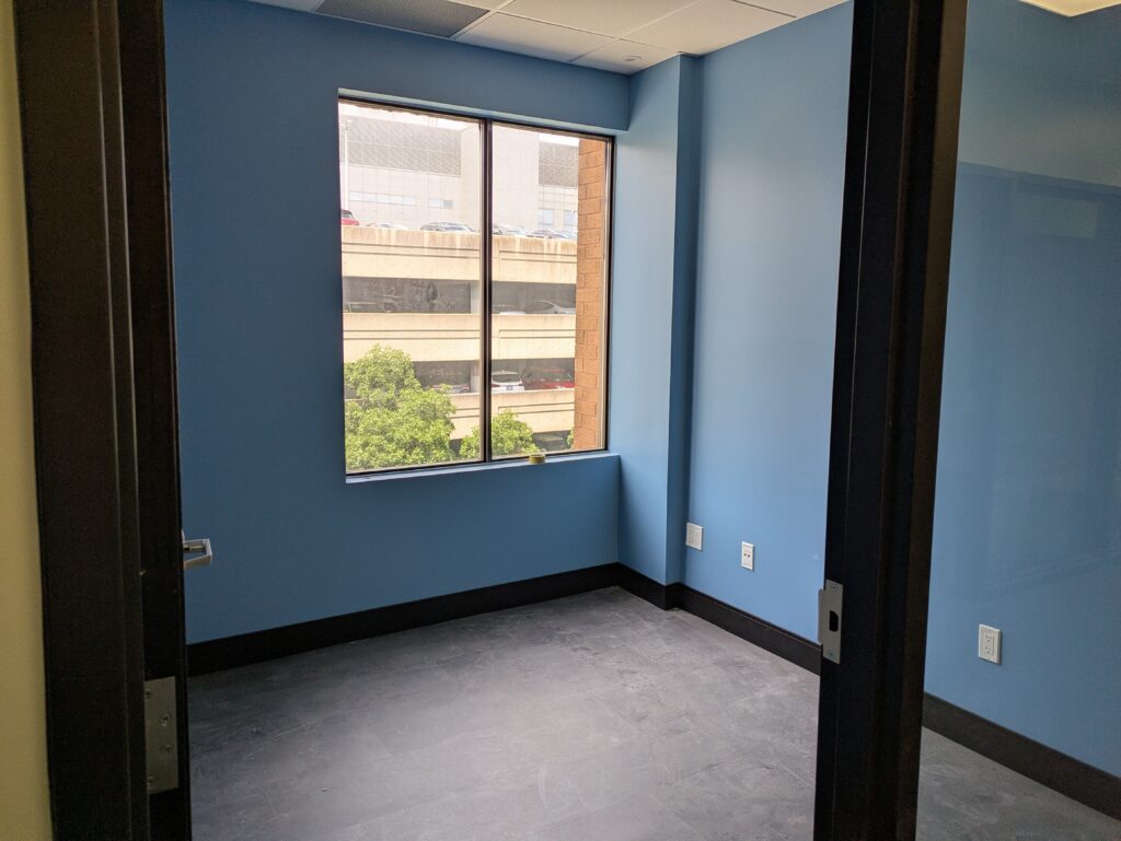 A room with blue walls and a big window.